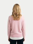 back view of a woman wearing a pink sweater on a plain background #color_almond-blossom