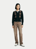 Person wearing a black argyle sweater and brown pants on a white background #color_black