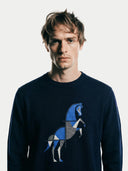 close up front view of a man wearing a navy sweater with a blue and gray geometric horse design on a white background #color_navy