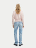 back view of a woman wearing light blue jeans and a pink sweater on a white background #color_peach-blush