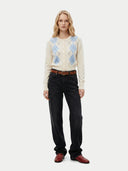 front view of a woman wearing a patterned sweater, black pants, and red shoes on a white background #color_coconut-milk