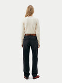 back view of a woman wearing a beige sweater and black jeans on a white background #color_coconut-milk