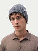 Man wearing a gray knit beanie with a brand logo on a light gray background. #color_charcoal