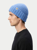 side view of a man wearing a blue knit beanie on a white background. #color_blue