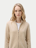 close up front view of a woman wearing a beige zip-up sweater against a light background. #color_beige