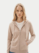 close up front view of a woman wearing a beige hoodie on a plain background. #color_beige
