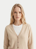 Woman wearing a beige cardigan over a white shirt on a light gray background. #color_beige