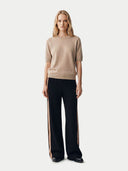Woman wearing a beige sweater and black pants with a side stripe on a white background. #color_beige