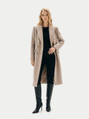 Woman wearing a beige coat and black pants on a white background. #color_taupe