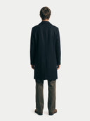 back view of a person wearing a black coat from behind on a white background. #color_black