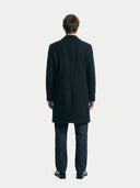 man wearing a black coat from behind on a white background. #color_black