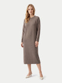 A woman modeling a long-sleeve, crew-neck midi dress in taupe brown, paired with beige pointed-toe heels, against a light gray studio background.