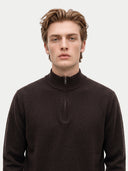 close up front view of a man wearing a dark brown quarter zip cardigan with mock neckline on a light gray background.