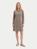 A woman modeling a long-sleeve, knee-length knit dress in a taupe-brown color, paired with beige loafers, against a light gray studio background.