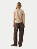 A model shown from the back wearing a beige knit sweater and dark brown wide-leg corduroy pants against a light gray studio background.