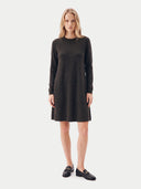 A woman modeling a dark brown long-sleeve knit dress with a crew neck and a flared silhouette, paired with black loafers, against a light gray studio background.
