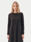 A blonde woman modeling a dark brown long-sleeve knit dress against a light gray studio background.