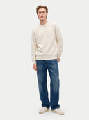 Man wearing a beige shirt and gray pants on a white background.