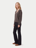 A woman modeling a dark brown V-neck knit sweater and black wide-leg trousers against a light gray studio background.