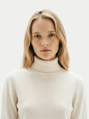 close up of a woman wearing a cream turtleneck sweater against a white background  #color_white