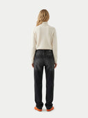 back view of a woman wearing black jeans and a light-colored sweater on a white background
