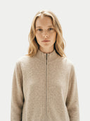 close up front view of a Woman wearing a beige zip-up jacket against a light background #color_beige