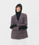 Person wearing a plaid blazer, black hood, gloves, and white pants on a light gray background