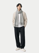 Man wearing a beige sweater, white shirt, black pants, and gray scarf on a white background #color_high-rise