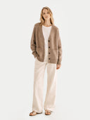 Woman wearing a brown cardigan over a white shirt and beige pants on a light gray background #color_taupe