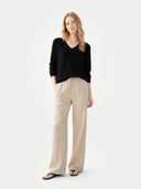 front view of a Woman wearing a black sweater and beige pants on a white background #color_black