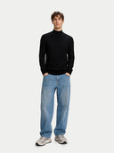Man wearing a black turtleneck and blue jeans on a white background #color_blue-graphite
