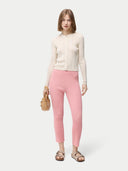front view of a woman is wearing a beige button-front cashmere silk cardigan with long sleeves, paired with pink pants. #color_whisper-white