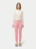 front view of a woman is wearing a beige button-front cashmere silk cardigan with long sleeves, paired with pink pants. #color_whisper-white