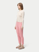 side view of a woman is wearing a beige button-front cashmere silk cardigan with long sleeves, paired with pink pants. #color_whisper-white