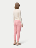 back view of a woman is wearing a beige button-front cashmere silk cardigan with long sleeves, paired with pink pants. #color_whisper-white