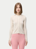 A woman is wearing a beige button-front cashmere silk cardigan with long sleeves, paired with pink pants. #color_whisper-white