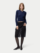front view of a woman wearing a navy blue button-front cashmere silk cardigan with a crew neckline and black skirt. #color_mood-indigo