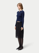 side view of a woman wearing a navy blue button-front cashmere silk cardigan with a crew neckline and black skirt. #color_mood-indigo