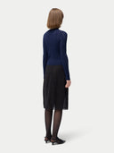 back view of a woman wearing a navy blue cashmere silk cardigan and black skirt. #color_mood-indigo
