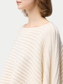 close up side view of a woman wearing a beige cashmere poncho. #color_white