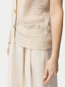 close up of a beige vest pocket and white skirt #color_off-white