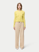 front view of a woman wearing a yellow cardigan with hidden buttons and beige pants on a light gray background. #color_blazzing-yellow