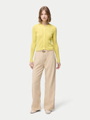 front view of a woman wearing a yellow cardigan with hidden buttons and beige pants on a light gray background. #color_blazzing-yellow
