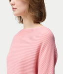 Person wearing a pink ribbed sweater on a light gray background