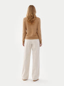 back view of a woman wearing a brown sweater and white pants on a white background #color_sheepskin