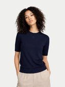 Woman wearing a navy blue sweater and beige pants on a light gray background #color_navy-blazer