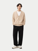 front view of a man wearing a beige cardigan, white shirt, black pants, and white sneakers on a white background #color_warm-grey