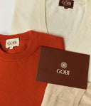 Two sweaters, one red and one beige, with 'Gobi' branding on labels and packaging.