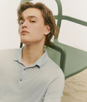 Person wearing a light gray polo shirt sitting on a green chair.