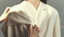 Person wearing a white kimono-style garment against a gray background